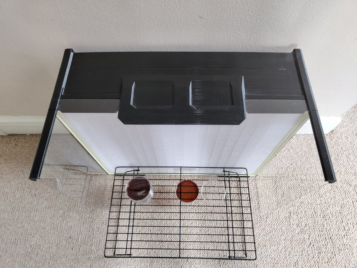 An extra-large laminar flow hood placed against a wall in a room, featuring a HEPA filter, acrylic shield, and a raised metal rack with Petri dishes.